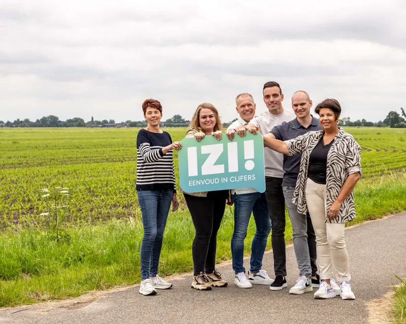 Het team van IZI! met het bord ‘IZI! Eenvoud in cijfers’ in de polder